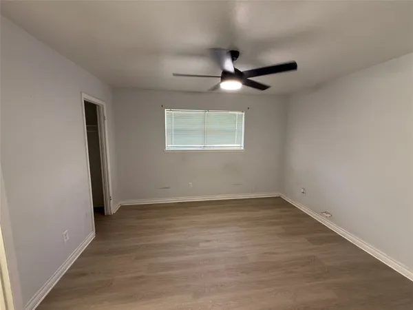 an empty room with wooden floor ceiling fan and windows