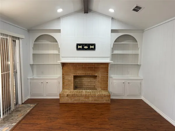 a view of a livingroom with an empty space & wooden floor kitchen view