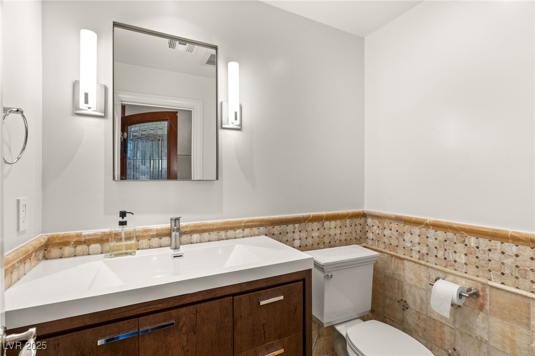 105 Quail Run Road Henderson, NV 89014 - Photo 18 of 88 Half bathroom with vanity, tile walls, and a wains