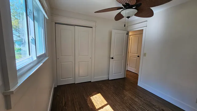an empty room with windows and fan