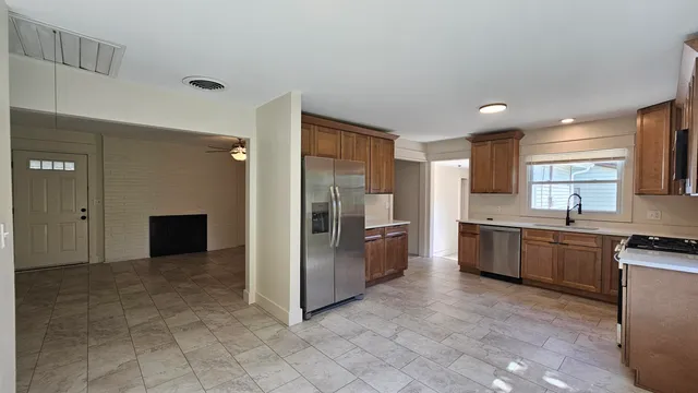 a large kitchen with stainless steel appliances kitchen island granite countertop a refrigerator and a sink