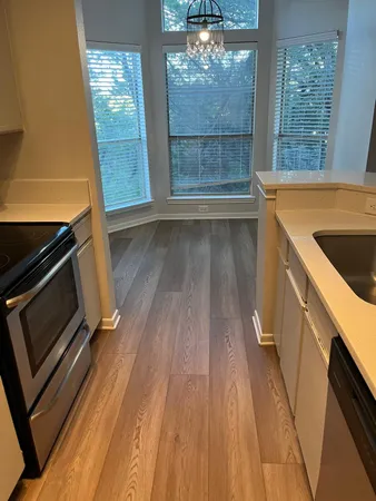 a view of a kitchen with wooden floor and stainless steel appliances