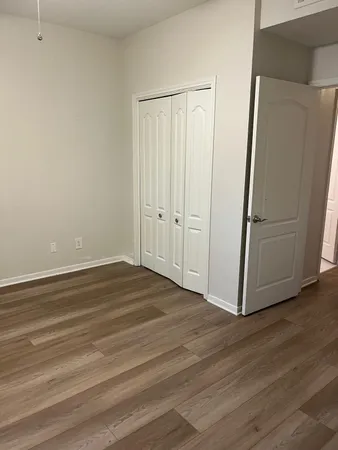 a view of a livingroom with wooden floor and a refrigerator