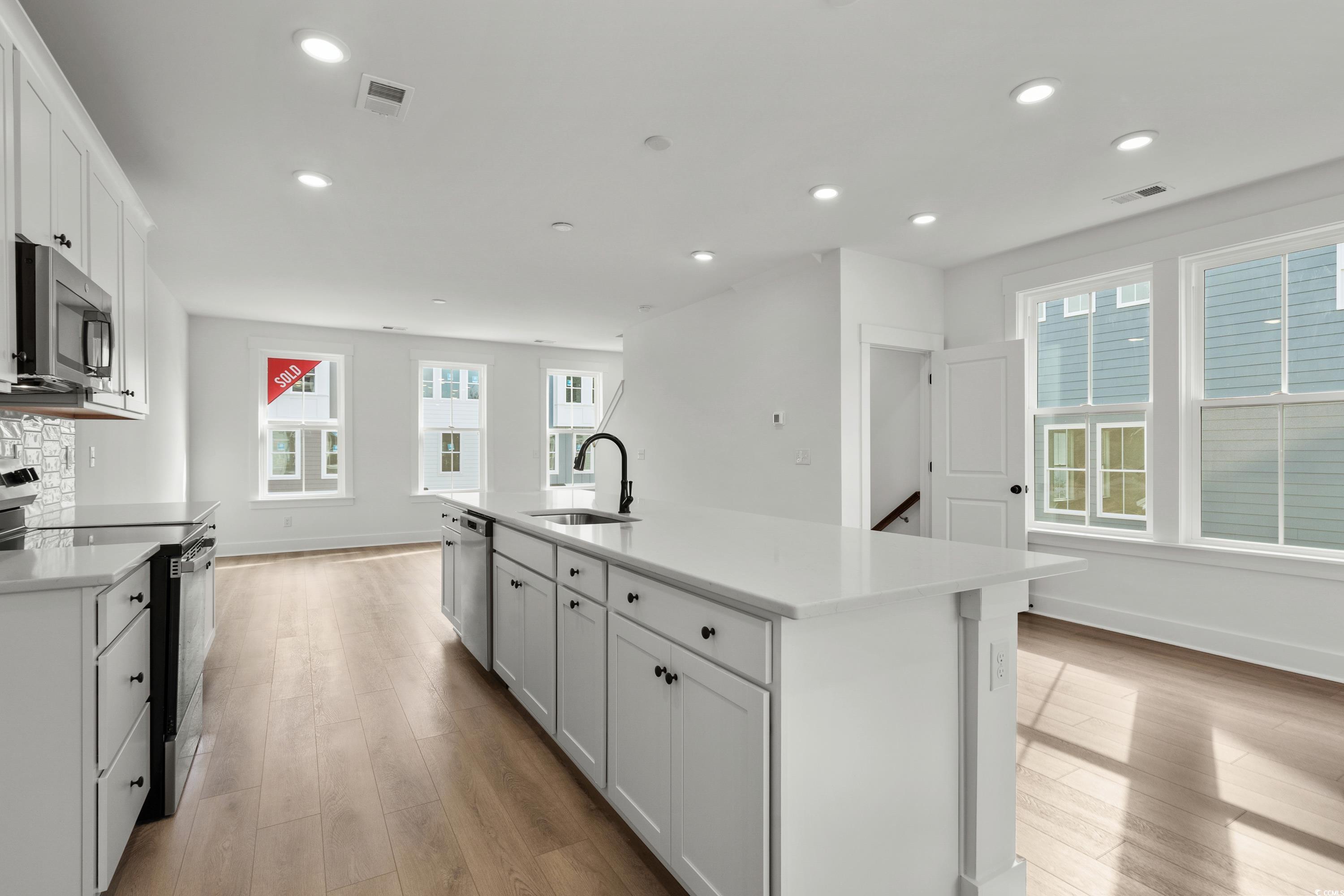 4414 Kingsport Road, Unit 1501 Little River, SC 29566 - Photo 9 of 30 Kitchen featuring stainless steel appliances, white cabinetry, a center island with sink, light wood-style flooring, and recessed lighting
