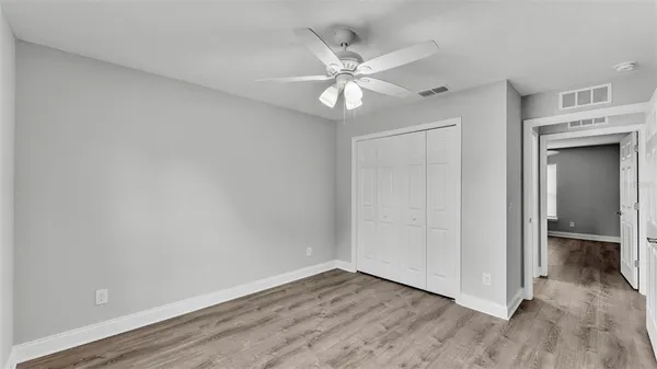an empty room with wooden floor closet and fan