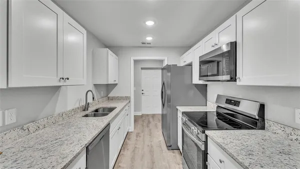 a kitchen with stainless steel appliances granite countertop a sink stove microwave and refrigerator