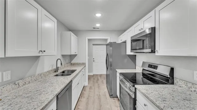 a kitchen with stainless steel appliances granite countertop a sink stove microwave and refrigerator