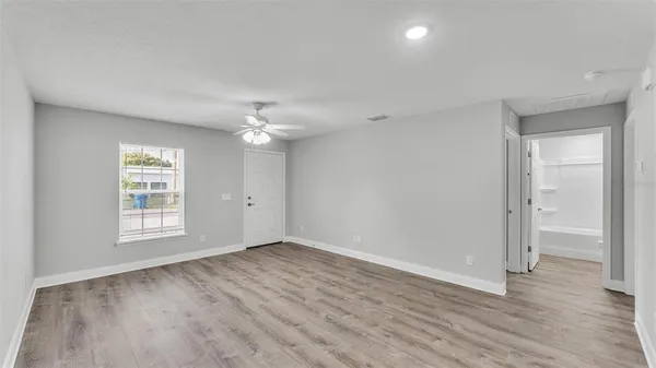 a view of an empty room with wooden floor and a window