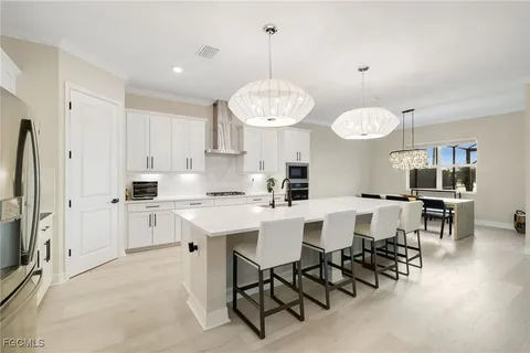 a kitchen with stainless steel appliances a table chairs sink and cabinets