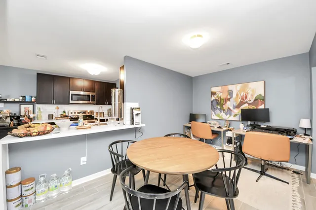 a dining room with stainless steel appliances a table and chairs in it