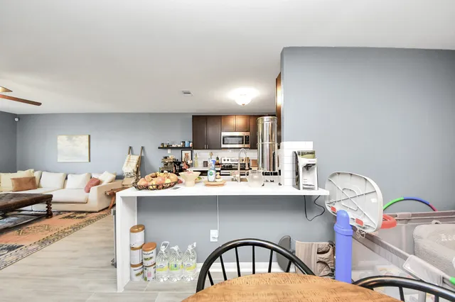 a kitchen with stainless steel appliances kitchen island granite countertop a stove top oven a sink dishwasher a dining table and chairs with wooden floor