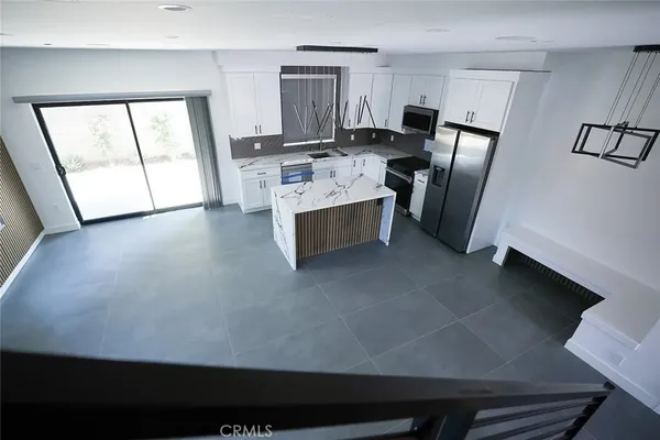 a kitchen with stainless steel appliances granite countertop a stove top oven a sink a refrigerator white cabinets and wooden floor