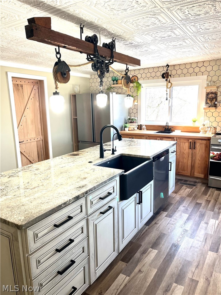 12972 Gilmore Road Southeast Port Washington, OH 43837 - Photo 11 of 50 Kitchen featuring an ornate ceiling, a kitchen island with sink, stainless steel appliances, light stone counters, and dark wood-style flooring
