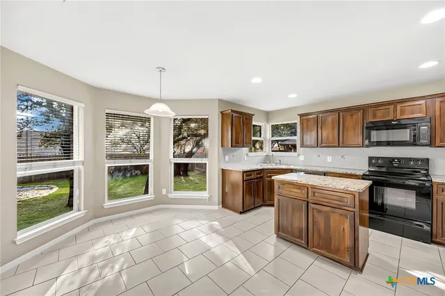 a kitchen with stainless steel appliances granite countertop a stove top oven a sink a counter space and cabinets