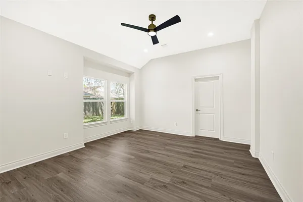 an empty room with wooden floor and ceiling fan