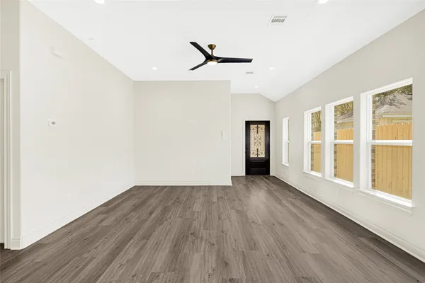 an empty room with wooden floor windows and ceiling fan