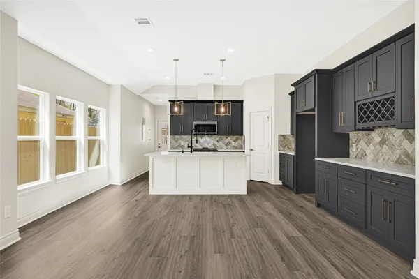 a large kitchen with a center island wooden floor stainless steel appliances and cabinets
