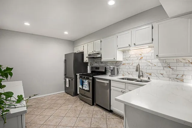 a kitchen with stainless steel appliances granite countertop a sink a stove a refrigerator and cabinets