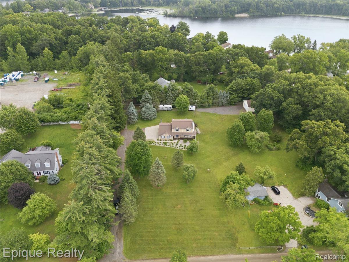 1221 Rhodes Road Lake Orion, MI 48360 - Photo 61 of 72 Spacious property featuring a large two-story residence with an elevated deck, extensive green lawns, and mature trees