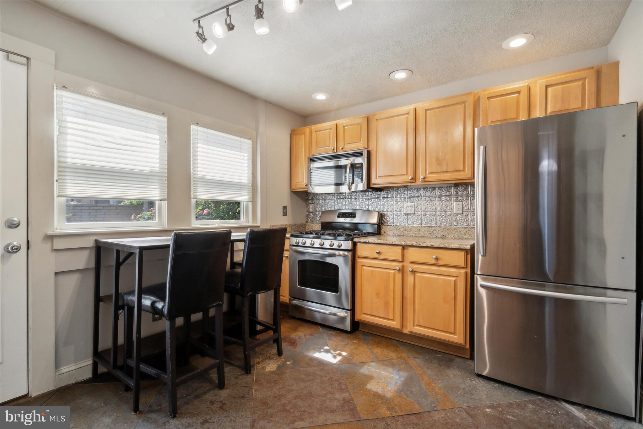 1640 Waverly Street Philadelphia, PA 19146 - Photo 5 of 16 a kitchen with stainless steel appliances granite countertop a refrigerator a stove a sink and a dining table with wooden cabinet