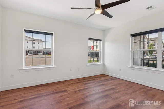 a view of an empty room with a window and wooden floor