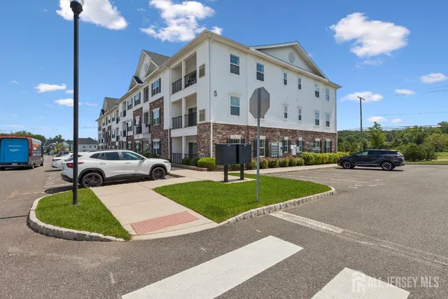 a view of a building with a garden and car parked