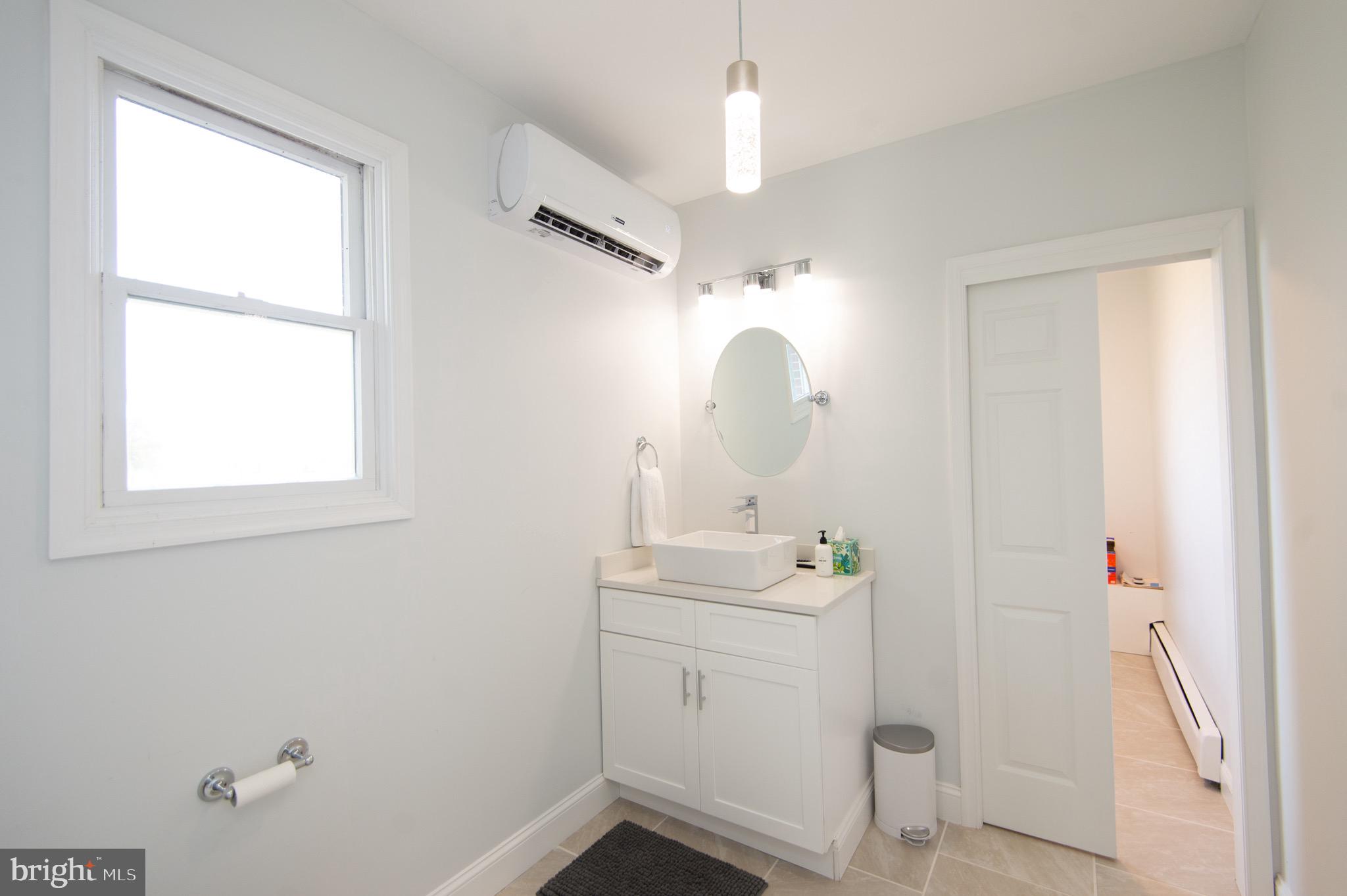 1417 School Street Cambridge, MD 21613 - Photo 48 of 73 a bathroom with a sink a light fixture and a window