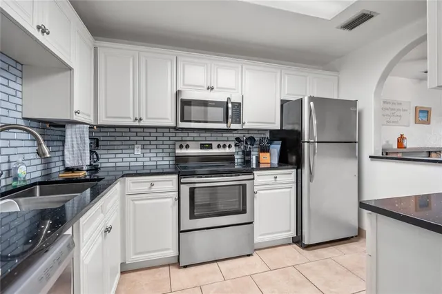 a kitchen with granite countertop white cabinets and white appliances