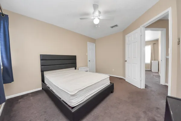 a spacious bedroom with a bed and a ceiling fan
