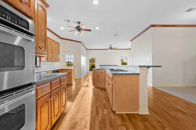 a kitchen with kitchen island granite countertop wooden floors and stainless steel appliances