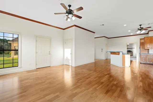 a view of an empty room with a window and wooden floor