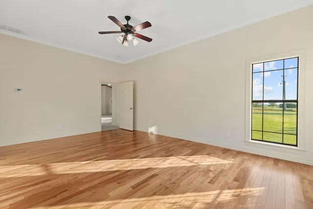 a view of a big room with wooden floor and a chandelier fan