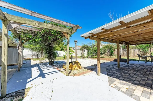 a view of a patio with a table and chairs under an umbrella with a barbeque