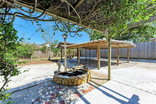 a view of a patio with table and chairs potted plants and large tree