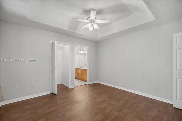 an empty room with wooden floor and fan
