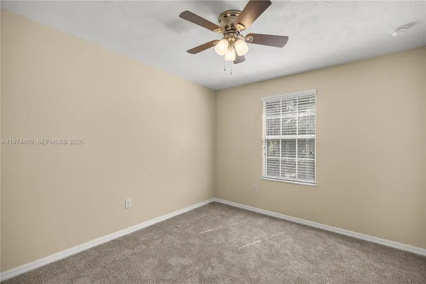 an empty room with a window and a fan