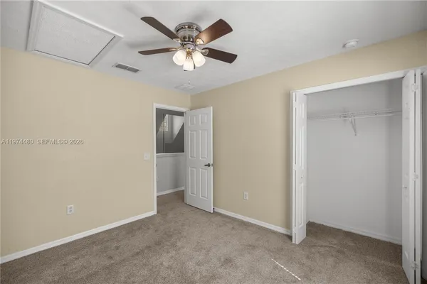 an empty room with a chandelier fan and windows