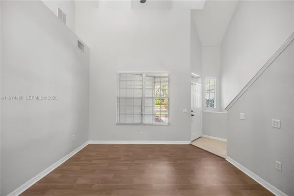 an empty room with wooden floor and windows