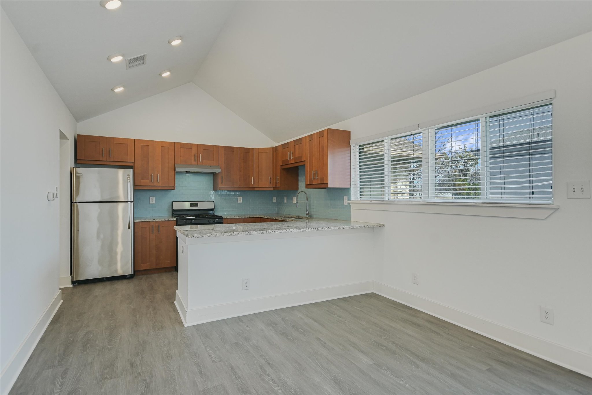 1311 East 52nd Street, Unit 2 Austin, TX 78723 - Photo 6 of 10 a kitchen with stainless steel appliances granite countertop a refrigerator a sink dishwasher a stove and a refrigerator with wooden floor