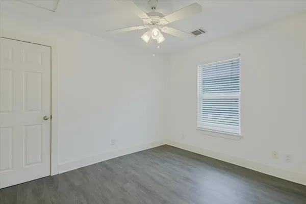 an empty room with a window and a fan