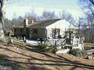 a view of a house with cars park side of road