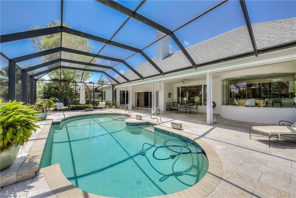 2260 Imperial Golf Course Boulevard Naples, FL 34110 - Photo 27 of 29 a view of a backyard with swimming pool table and chairs under an umbrella