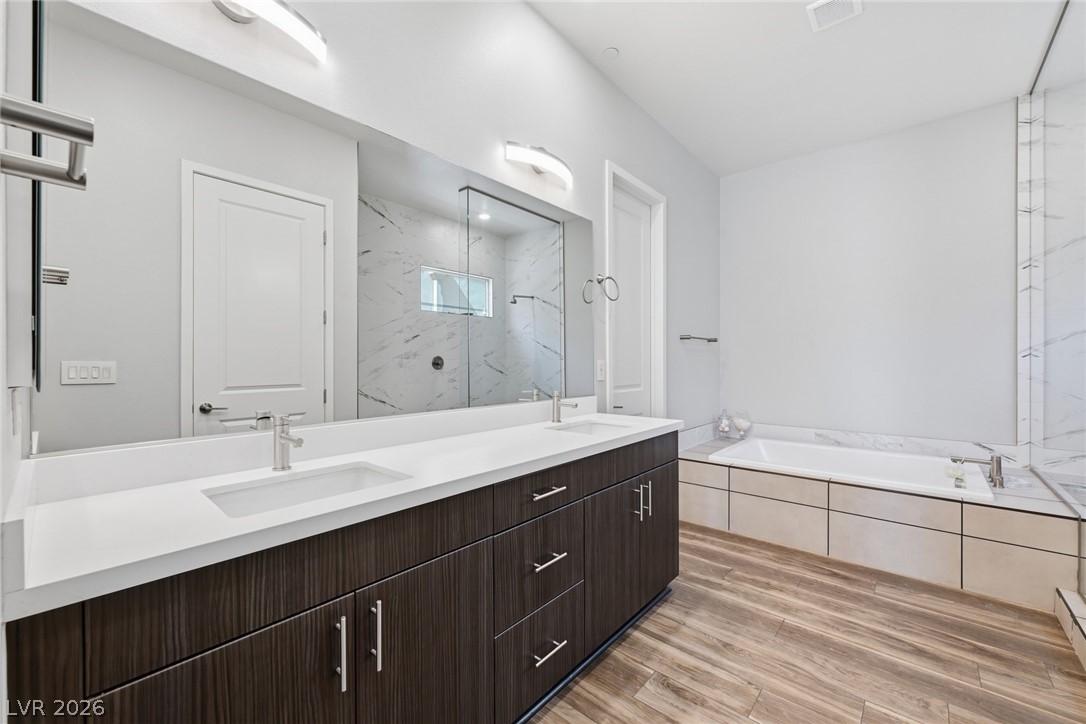 4246 Swift Street Las Vegas, NV 89135 - Photo 36 of 71 Bathroom featuring double vanity, a marble finish shower, light wood-type flooring, and a bath