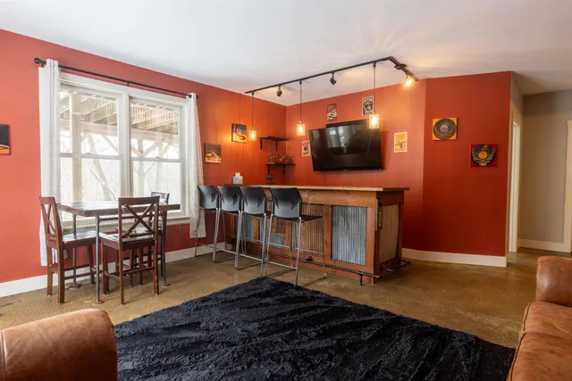 a living room with furniture a flat screen tv and floor to ceiling window