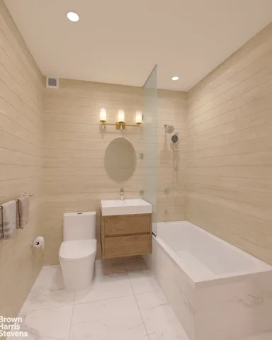 a spacious bathroom with a toilet a sink a mirror and bathtub