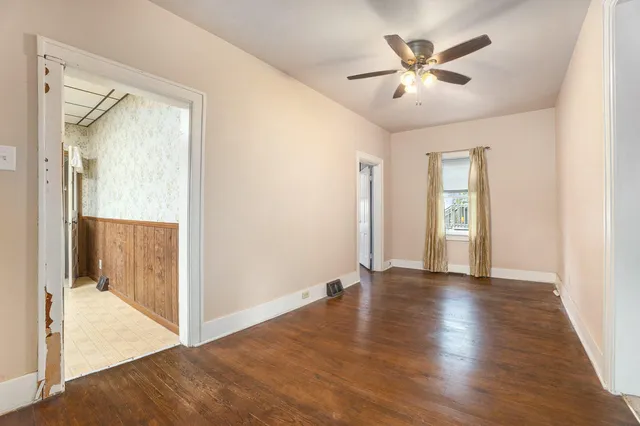 a view of an empty room and bathroom with wooden floor