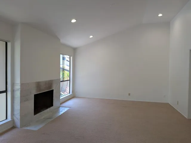 an empty room with windows and fireplace