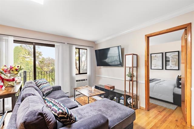 208 1st Street, Unit 5B Hoboken, NJ 07030 - Photo 5 of 11 a living room with furniture a flat screen tv and a floor to ceiling window