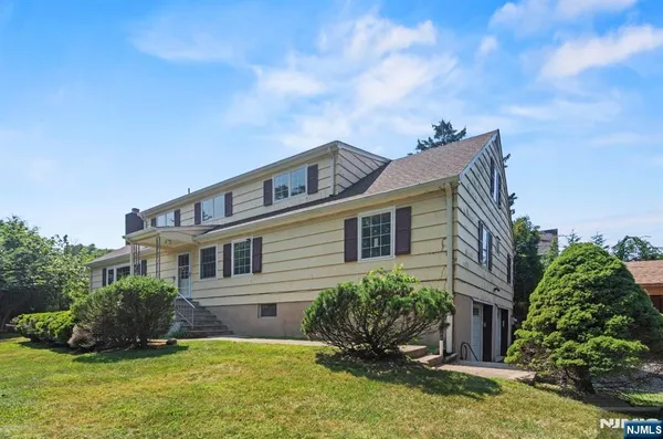 a house that has a big yard and potted plants in front of it
