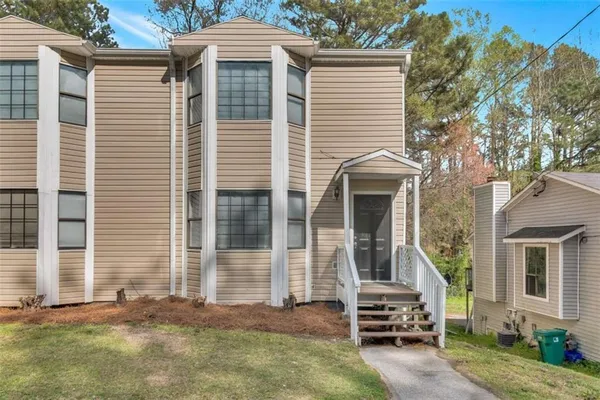 a view of a house with a yard and large tree